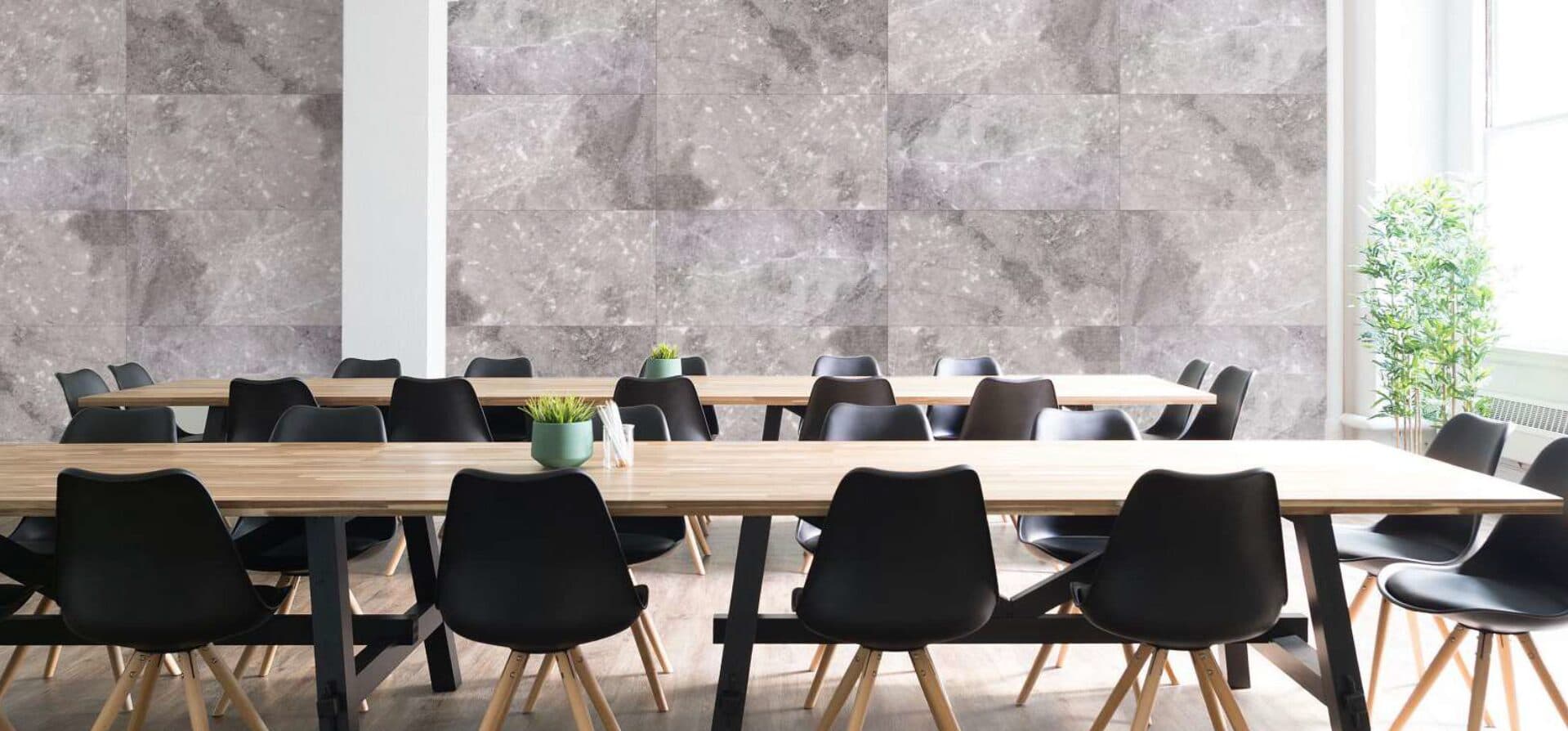 Long shared work table below a stone-print acoustic wall